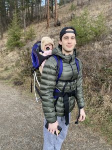 Photo of Ryan Coneely with baby in a backpack.