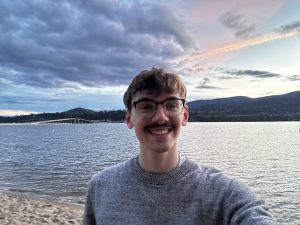 Justin takes a selfie in front of the Okanagan Lake on the beach with the sun setting